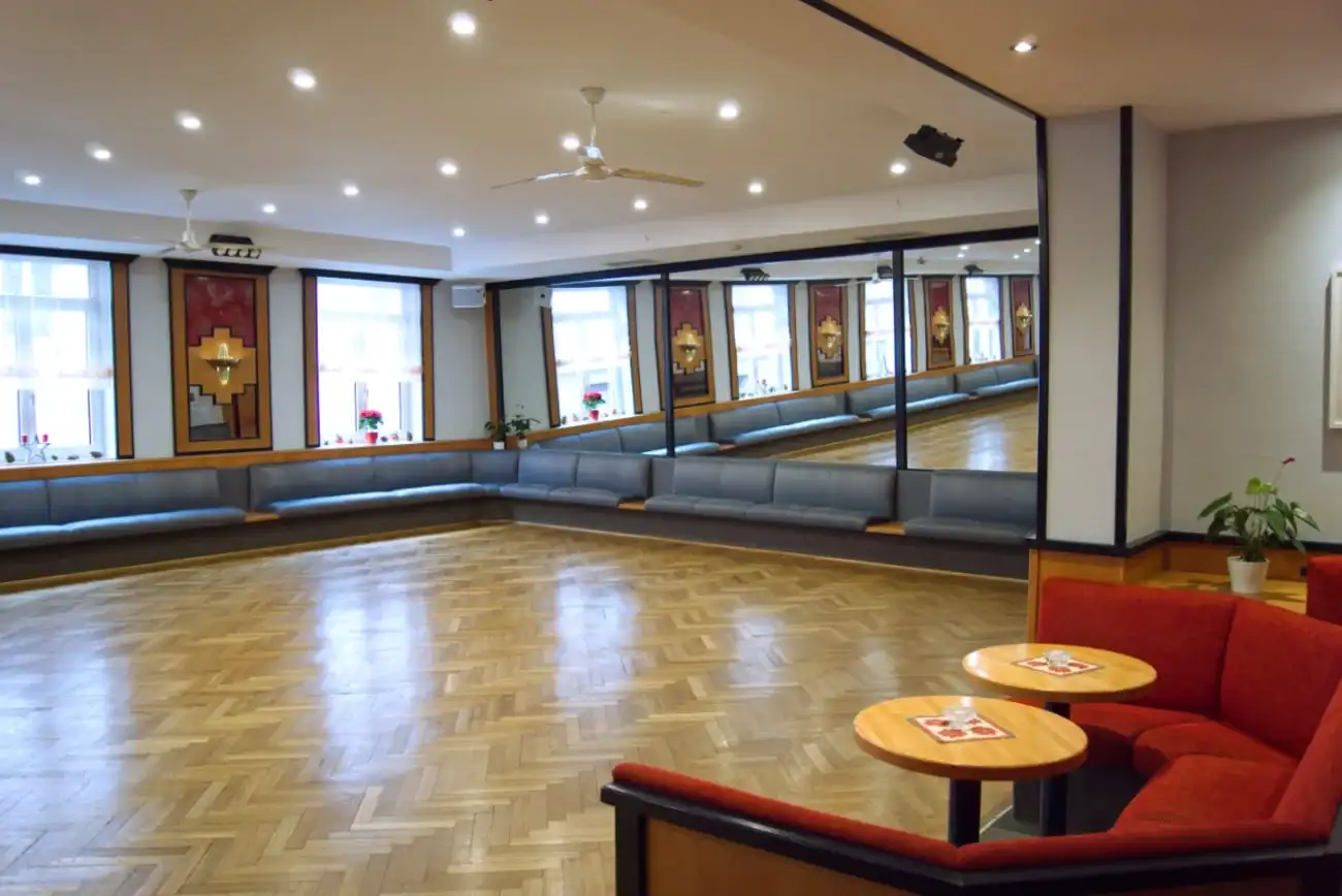 Oberer Saal mit einer Tanzfläche und großen Spiegeln, die den Raum reflektieren.