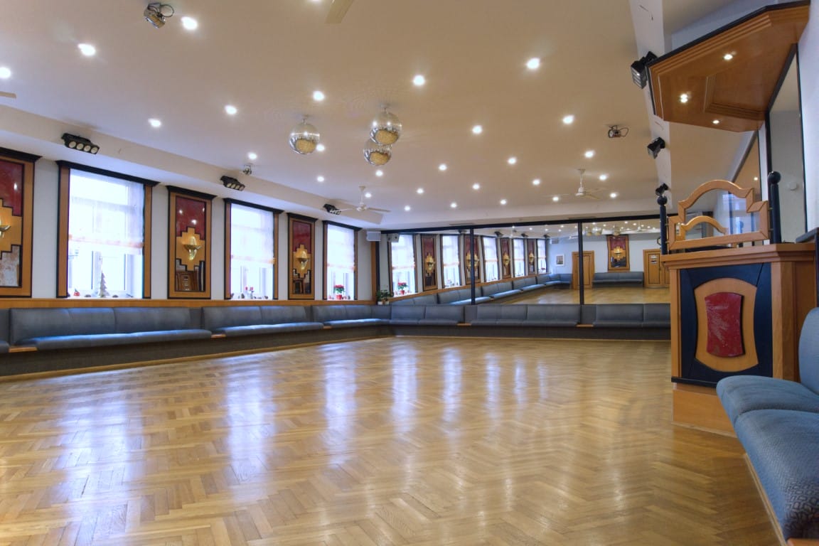 Oberer Saal mit einer roten Sitzecke, Tanzfläche und großen Spiegeln, die den Raum reflektieren.